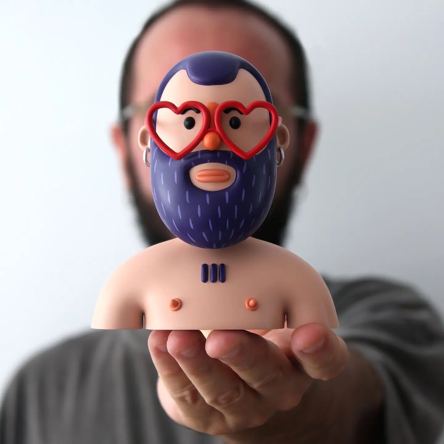 Mr. Cokis resin bust held in an open hand: blue beard, red heart-shaped glasses