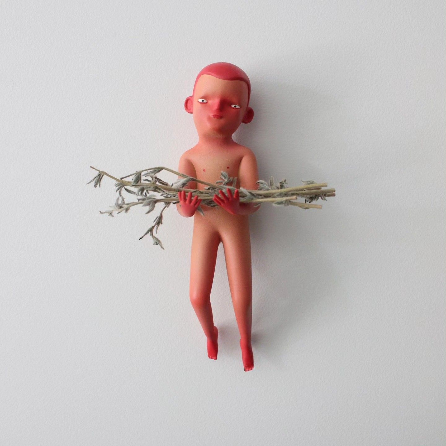 Red-haired figure on a white wall holding a dried branch