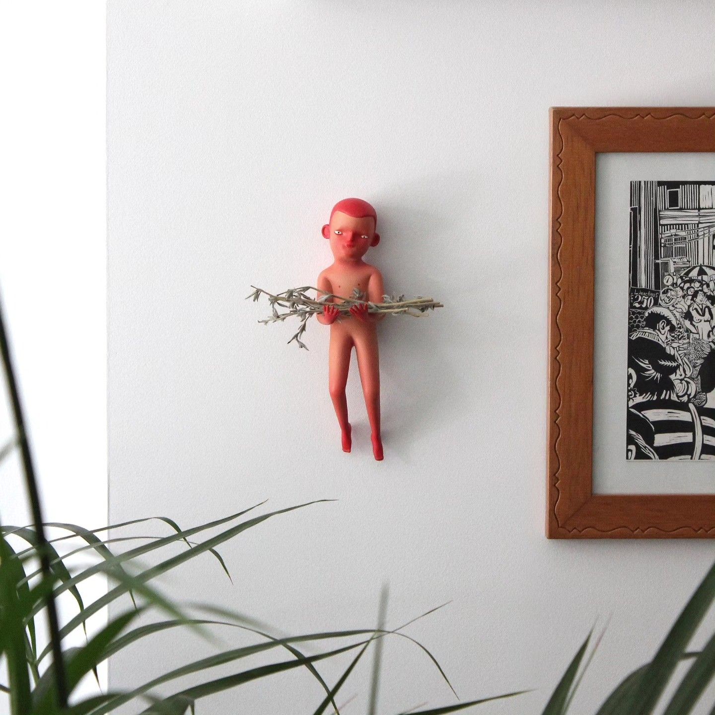 The figure in a home, next to a framed print and a plant