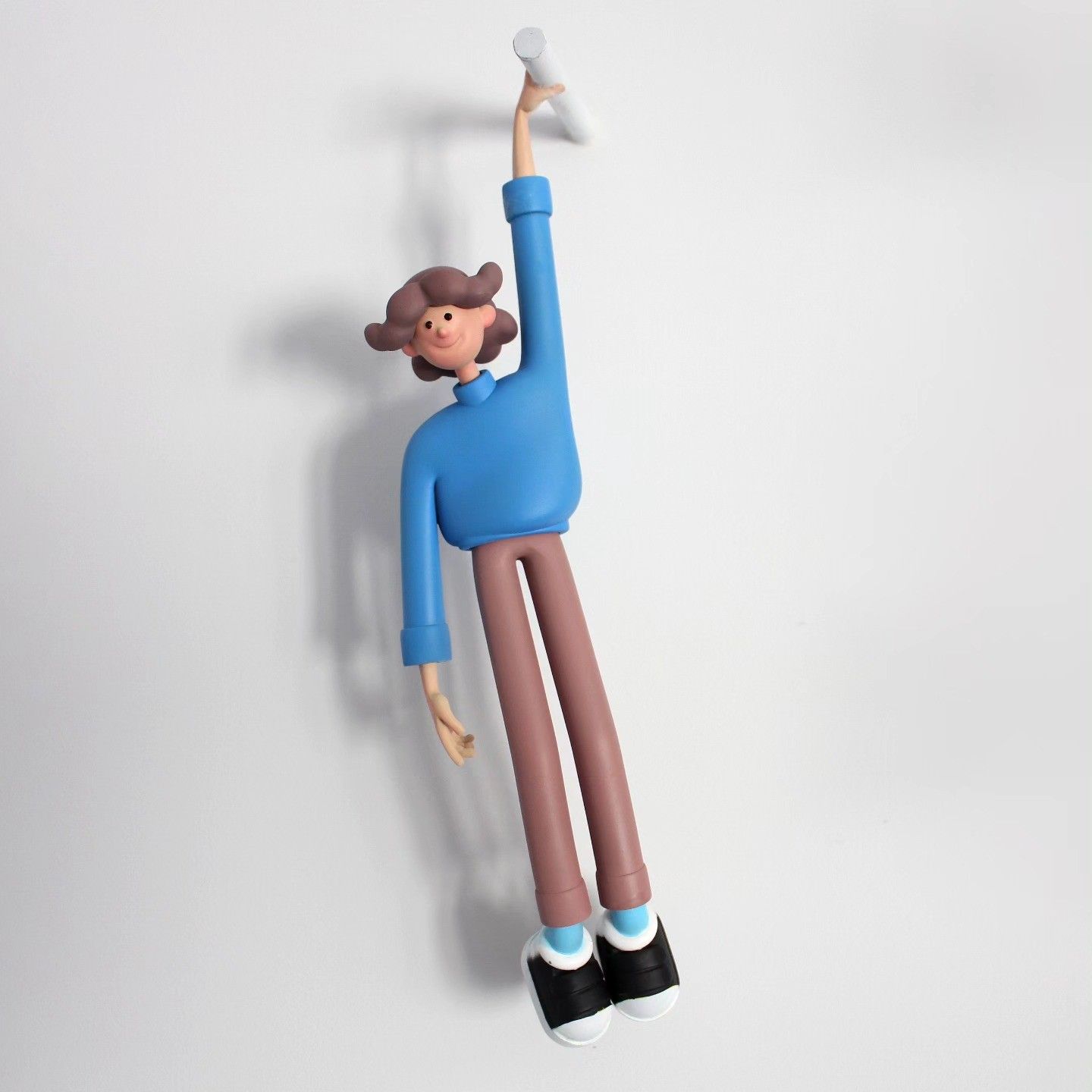 Wall Toy hanging from a hook on a white wall: blue jumper, long brown trousers